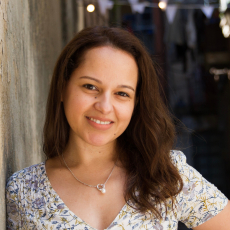 Person with long wavy hair smiles at camera.