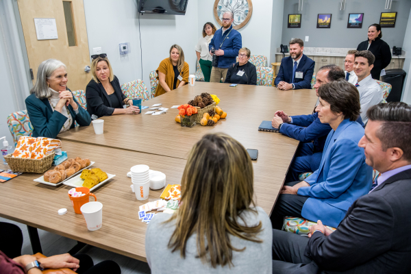 Many adults smile and talk around a conference table