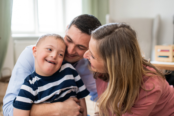 Parents sit on floor with young child, smiling