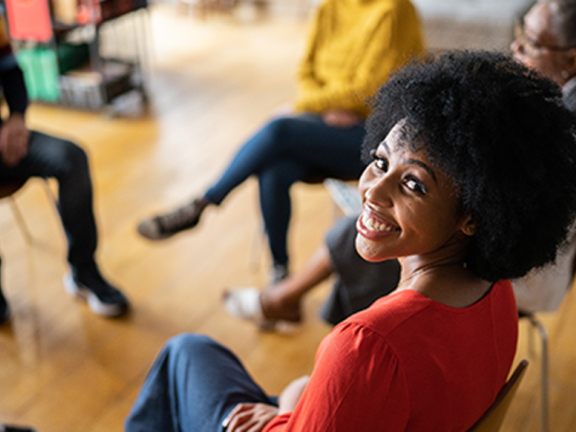 woman smiling whilst sitting in a circle group