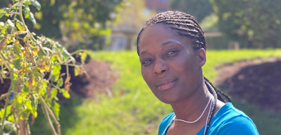 Magdalene Dessources-Osias smiling outside. She is wearing a blue shirt.