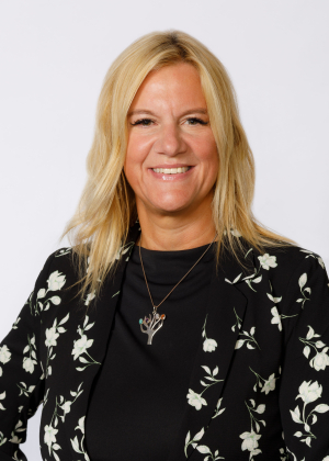 Adult with shoulder length blond hair smiles at the camera