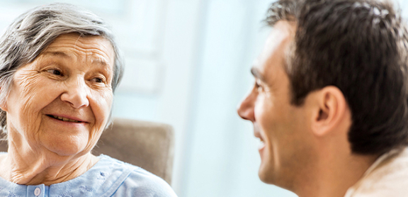 A senior-aged woman holding her adult son's hand