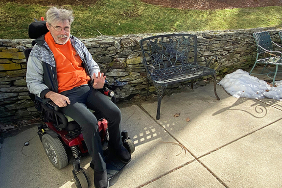 Jim sitting in his wheelchair outside smiling