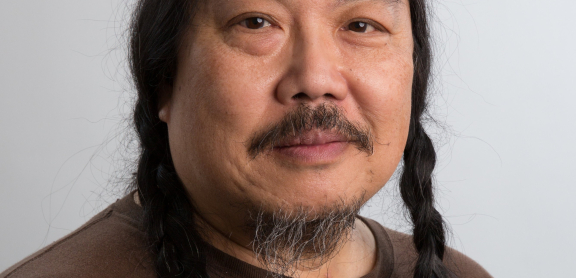 Headshot of a smiling middle-aged Asian adult with two long dark braids