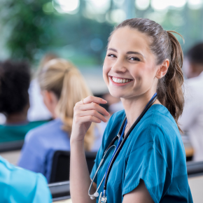 Adult with long hair and stethoscope smiling