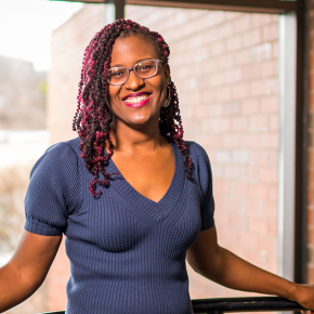 A woman standing by a window and smiling