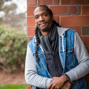 A man leaning on a brick pillar with garden in the background