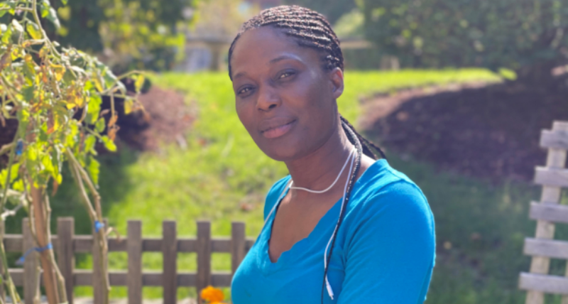 A woman smiling outside in a garden