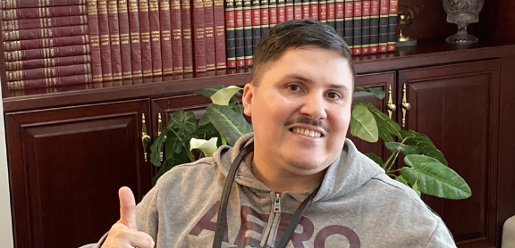 Man sitting in a chair giving two thumbs up