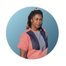 Person with shoulder length hair and peach and blue shirt smiles at camera